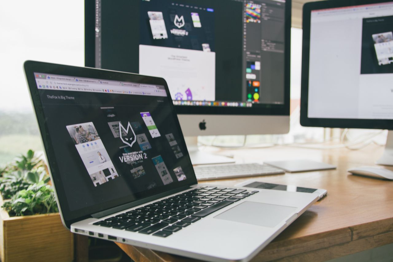 Un espace de travail élégant, avec un ordinateur portable et des écrans affichant un logiciel de design.